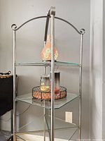 Full view of silver metal display stand with three glass shelves