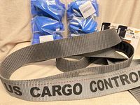 Gray US Cargo Control cargo strap, two blue ski strap sets, partial view of batteries