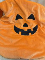 Full view of orange costume back with jack-oʼ-lantern face
