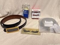 All four items laid out: belt, eyelashes, ornament box, keychain package