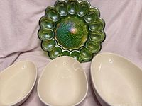 Set showing green deviled egg tray and three cream ceramic bowls