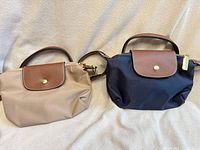 Front view of both navy and beige crossbody bags