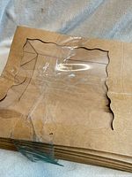 Stack of flat bakery box blanks showing window cut-outs, tape on surface