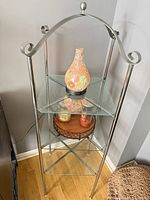 Full view of brushed nickel metal and glass display shelf in corner