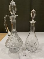 Both crystal decanters with stoppers displayed side by side