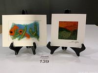 Both felted artworks displayed on easels