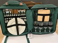 Open backpack showing full picnic set, plates, cutlery, glasses, board