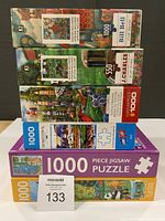 Stack of six jigsaw puzzle boxes showing piece counts and assorted artwork
