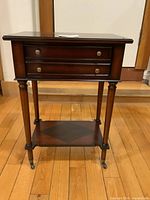 Full view of Bombay Company side table front showing drawer, legs, lower shelf, casters