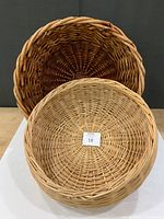 Two large round wicker baskets stacked showing size and finishes