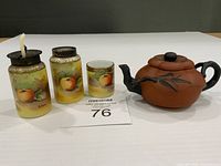 Group shot showing three condiment jars, spoon, and purple clay teapot