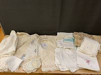 Wide view of assorted folded lace and linen pieces on tabletop