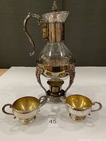 Front view of carafe assembled on stand with creamer and sugar