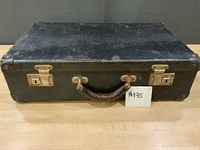 Top view of closed black McBrine travel case, showing handle, latches, wear