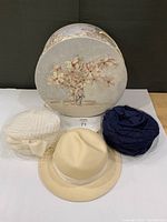 Group shot showing three hats and floral hat box