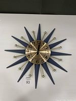 Front view of starburst wall clock showing face, hands, rays