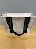 Front view cream tote with black logo straps