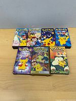 Seven Pokémon VHS tapes laid face up on wooden surface