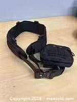 Black nylon tactical belt laid flat with attached pouch visible