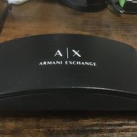 Black hard shell case displaying A|X Armani Exchange logo