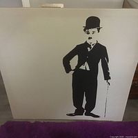 Full view of framed painting showing entire Charlie Chaplin figure on cream background