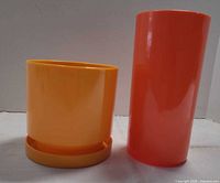 Yellow planter with saucer beside taller orange planter