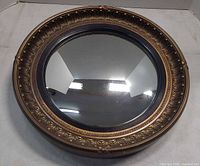 Front view of round gilded mirror showing ornate frame and glass