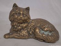 Front view of brass cat figurine showing patina and verdigris