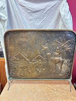 Front view of embossed copper fireplace screen with camel and pyramid scene