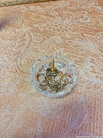 Top view of cut glass dish with gold-tone cone holding assorted gold-tone jewelry pieces
