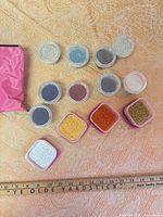All containers of seed beads with ruler for scale