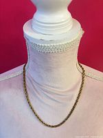 Full view of gold tone rope chain necklace on display bust