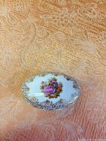 Closed Limoges trinket box showing lid artwork and gilt trim