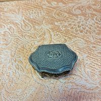 Closed hexagonal metal jewelry box, embossed top