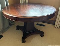 Full view of round walnut pedestal table showing base and top