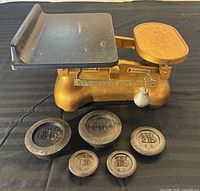 Full view of Avery balance scale with black tray, round plate and three disc weights