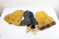 All three pairs of men’s mittens and baby moccasins laid out