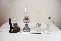 Front view showing all four oil lamps lined up for scale and comparison, ruler for height reference