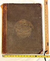 Front cover showing cloth boards, leather spine and corners, tape measure for scale