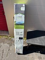 Front of boxed Real Living pop-up sun shelter showing branding and 8x10 size
