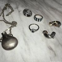 Overview of necklace, three rings, pair clip-on earrings
