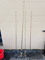 Full view of four fishing rods leaning against wall