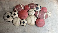 Full view of metal sports ball wall art piece on concrete floor
