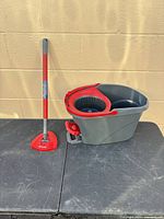 Bucket and mop handle standing on table, showing overall lot
