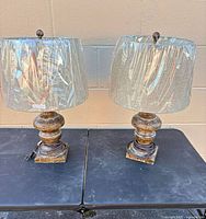 Front view of both matching rustic distressed table lamps with shades wrapped in plastic