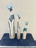 Front view of the three carved wooden cat sculptures standing side by side