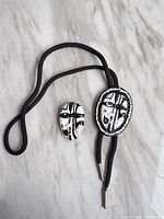 Bolo tie and brooch full view on marble surface