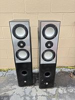 Front view of both floor speakers showing drivers, ports, cabinets