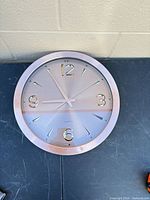 Front view of round rose gold quartz wall clock showing face, numerals and hands