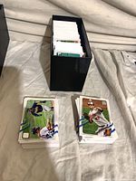 Box filled with baseball cards, additional stacks beside box